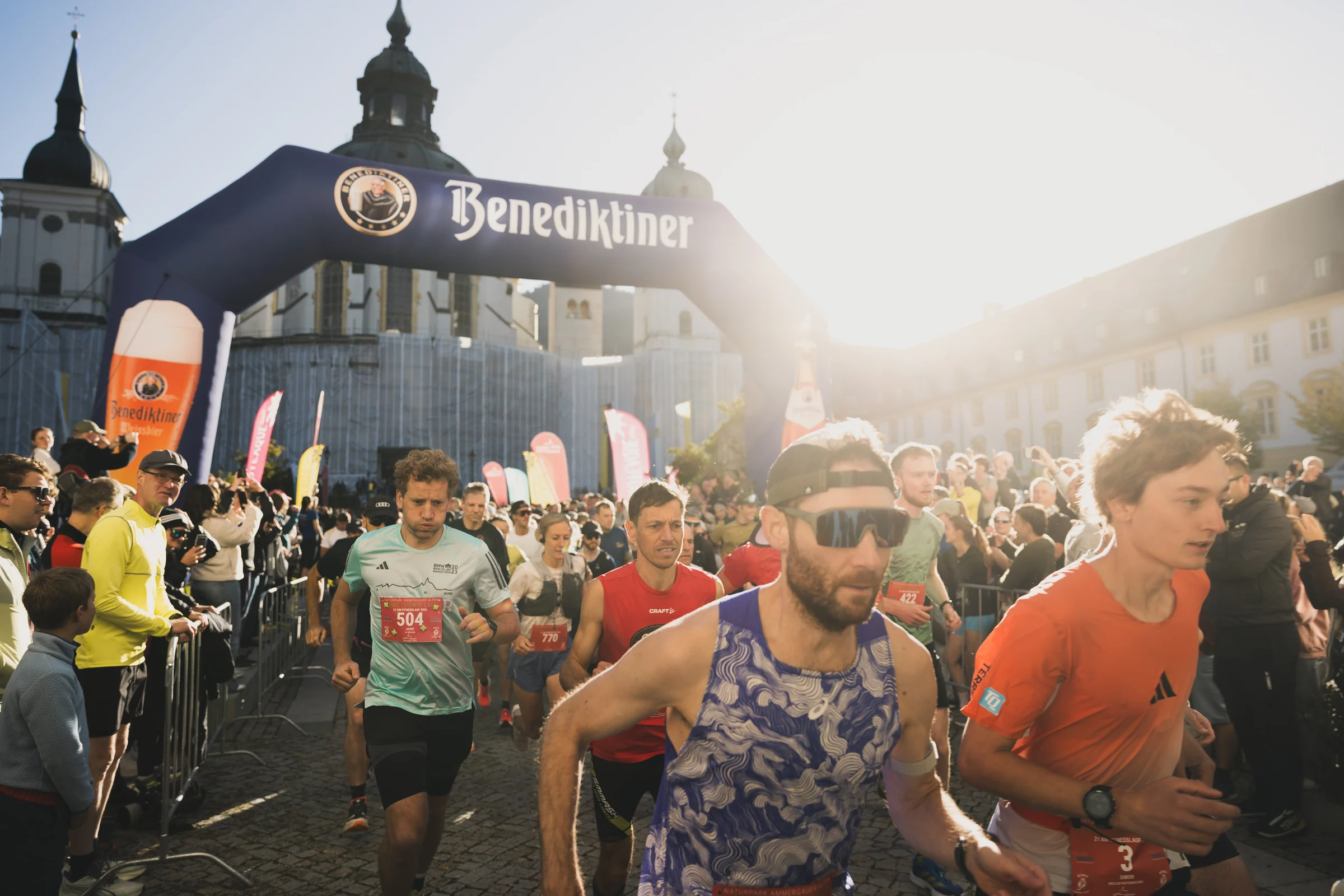 Laufende starten im warmen Sonnenlicht vor dem Kloster Ettal.