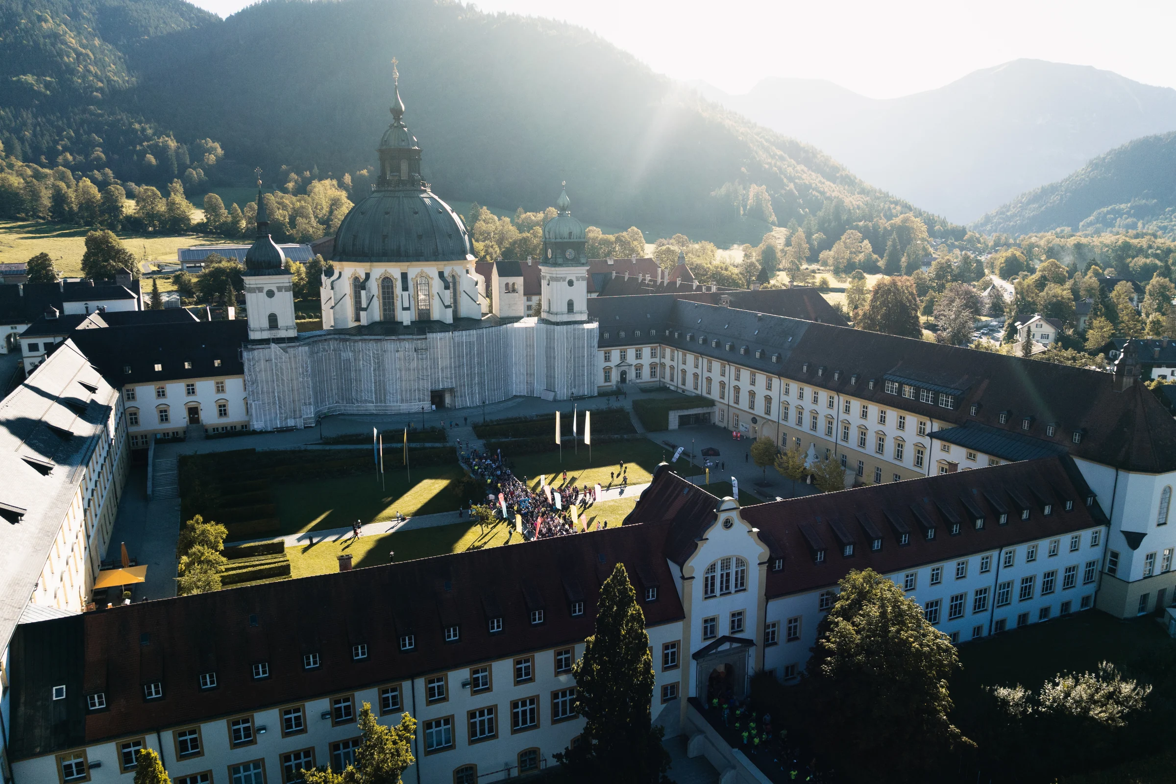 Luftaufnahme des Klosters Ettal mit der Laufveranstaltung im Innenhof und Bergen im Hintergrund.
